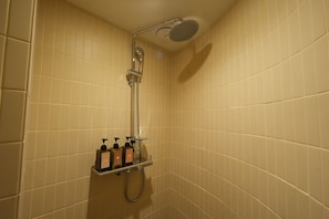 Ducha con cabezal de ducha de mano y panel de control en la pared con dispensadores de jabón.