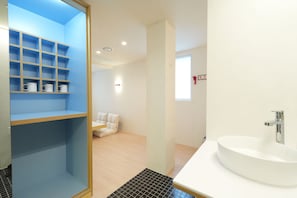 A modern bathroom with a white sink, a blue storage unit with shelves, and a white toilet.