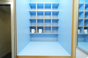 Un baño con pared de azulejos azules, un tocador de madera con espejo y una repisa con una taza blanca.
