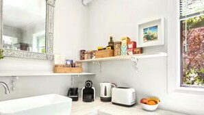 A modern kitchen with a white countertop, a sink, a toaster, a kettle, and a bowl of fruit. - “Highly rated Blackheath garden studio — 4.94 from over 1,000 Airbnb guests” (Blackheath)