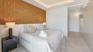 A modern hotel room with a large bed, a wooden accent wall, and a nightstand with a lamp. - VILLA STATUS BY VACATION MARBELLA (Estepona)