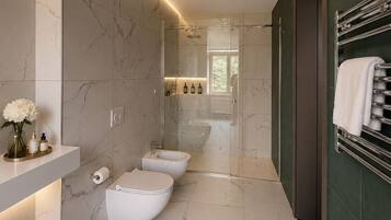 Un baño moderno con piso de mármol, ducha con mampara de vidrio y un perchero para toallas.