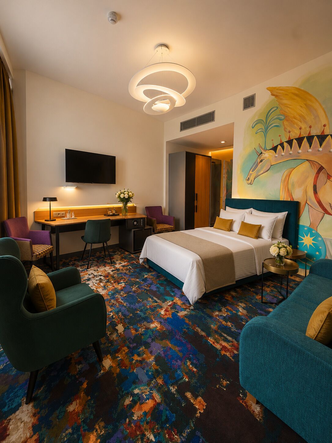 A hotel room with a bed, a desk, a TV, and a colorful carpet.