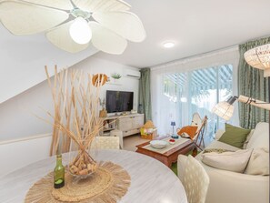 A modern living room with a dining area, a flat-screen TV, and a ceiling fan. - Arabella by Interhome (Peñiscola)