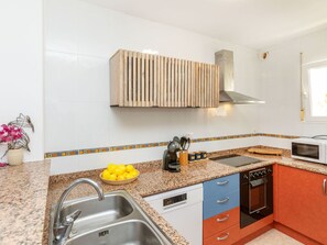 Uma cozinha moderna com uma pia de aço inoxidável, forno embutido e micro-ondas.