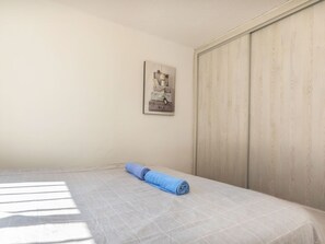 A bedroom with a bed, a rolled-up towel, a wall-mounted picture, and a wooden wardrobe. - Alondras by Interhome (Peñiscola)