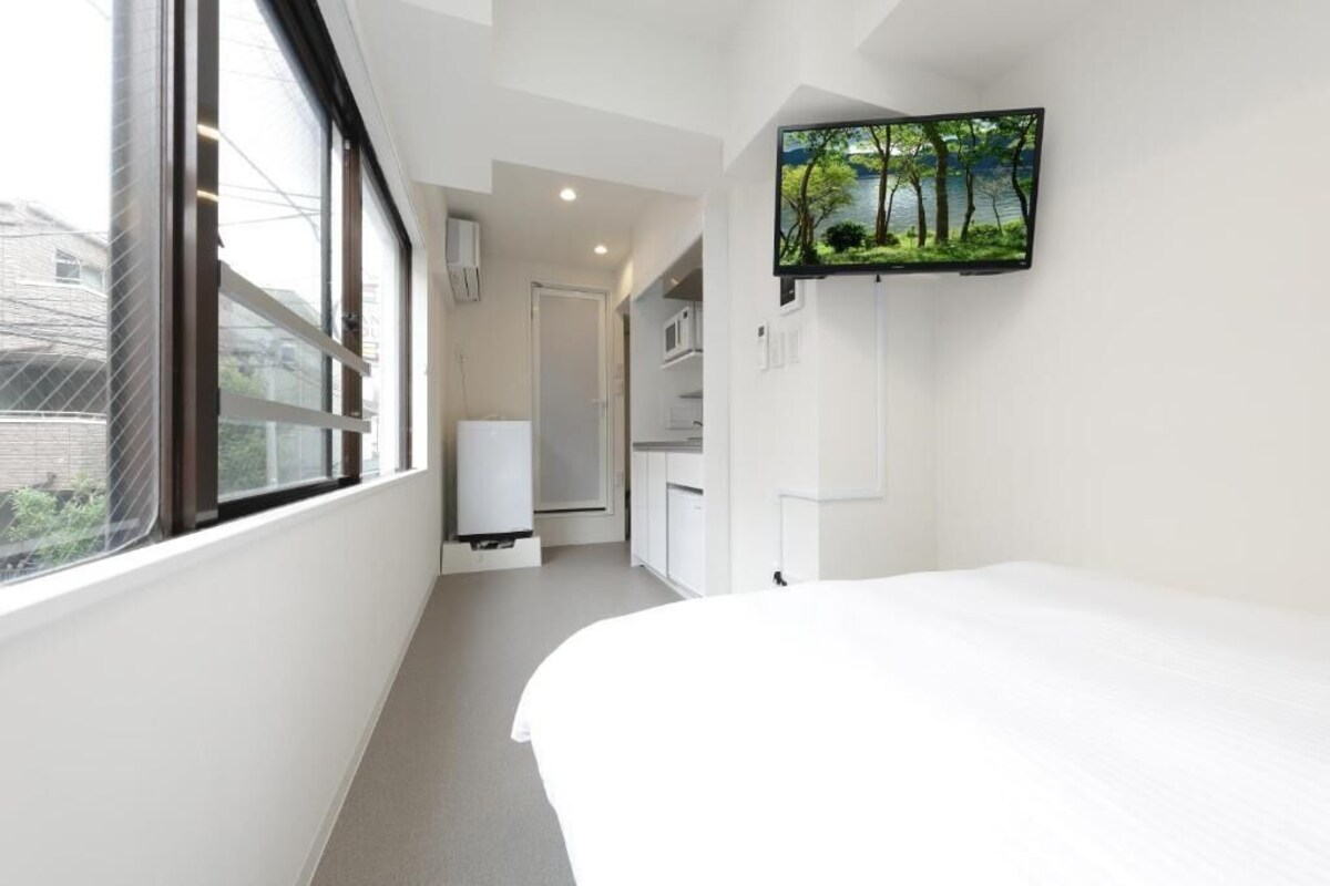 Une chambre d’hôtel équipée d’un lit, d’un téléviseur fixé au mur et d’une fenêtre donnant sur l’extérieur.