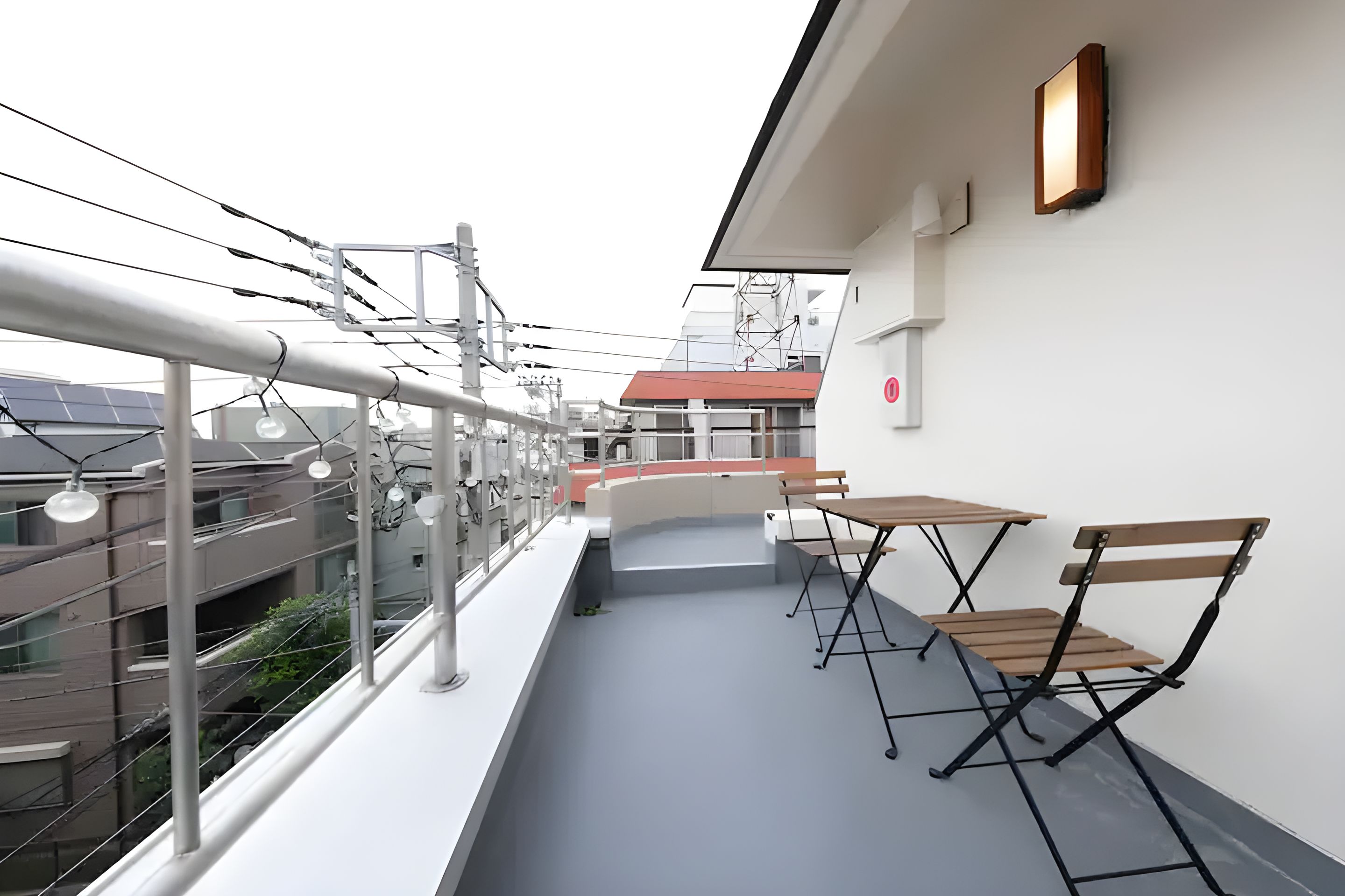 A balcony with a table and chairs, a railing, and a view of buildings.