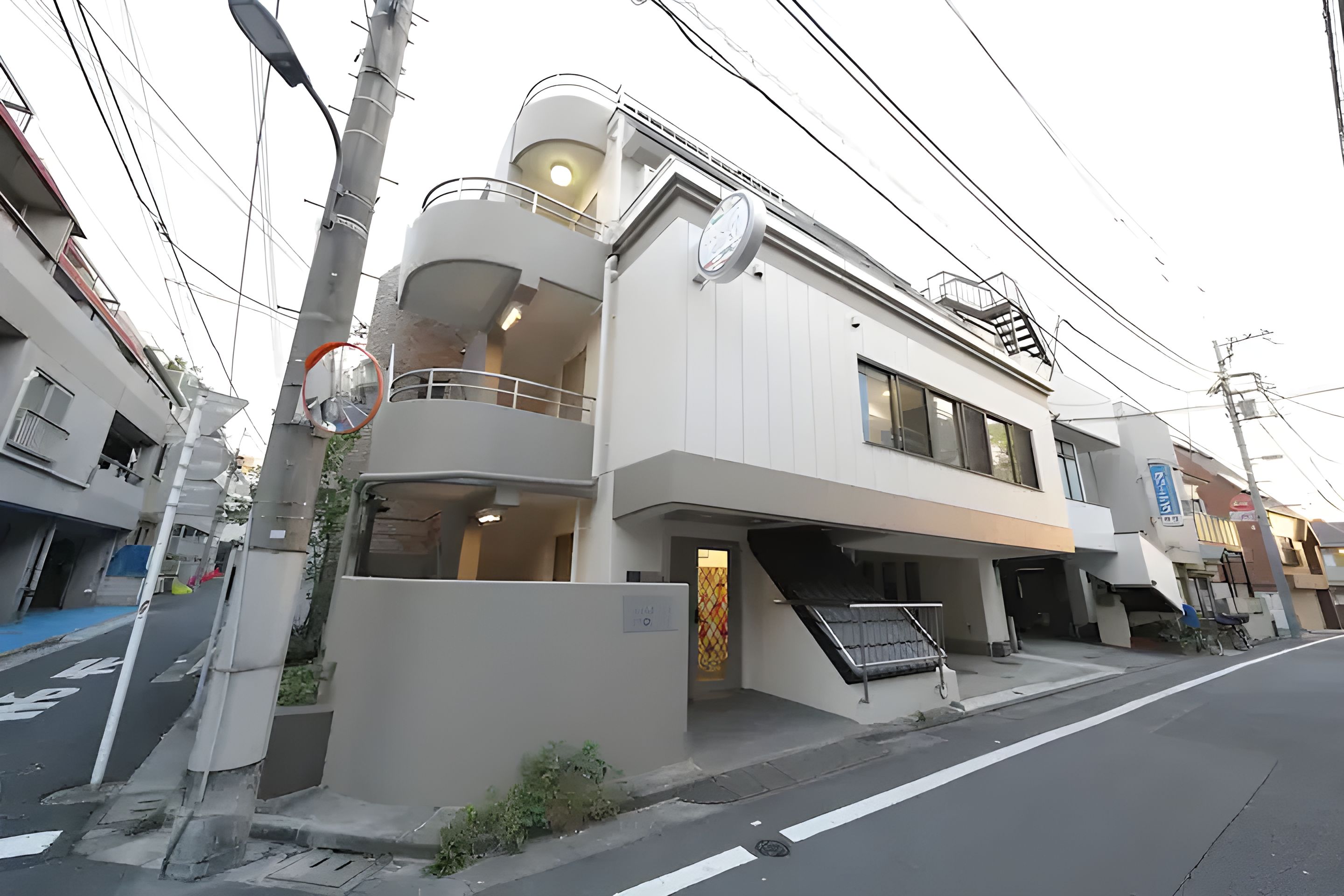 A modern multi-story building with a balcony, a staircase, and a signboard.