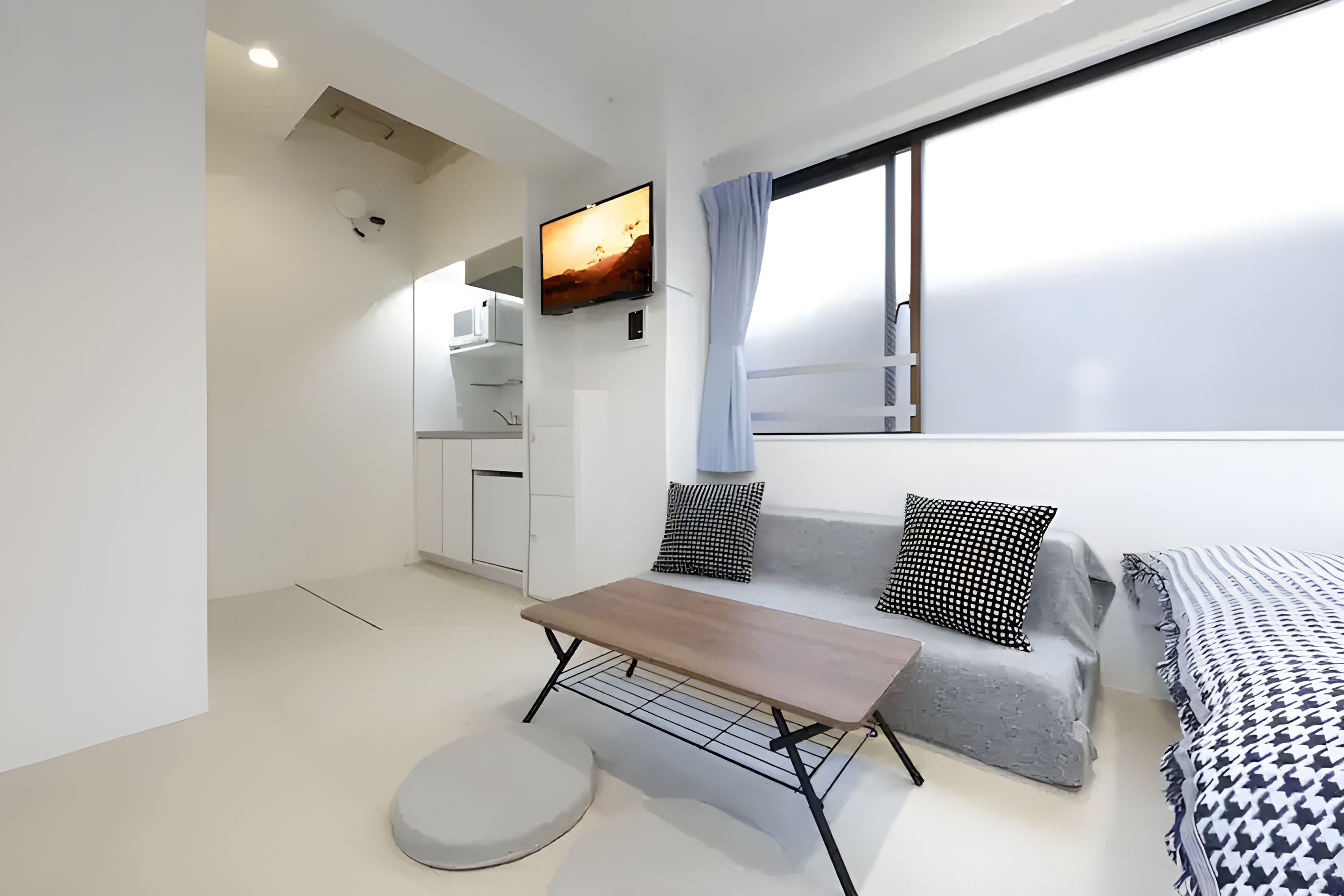 A modern, minimalist room with a sofa, a small table, and a television mounted on the wall.