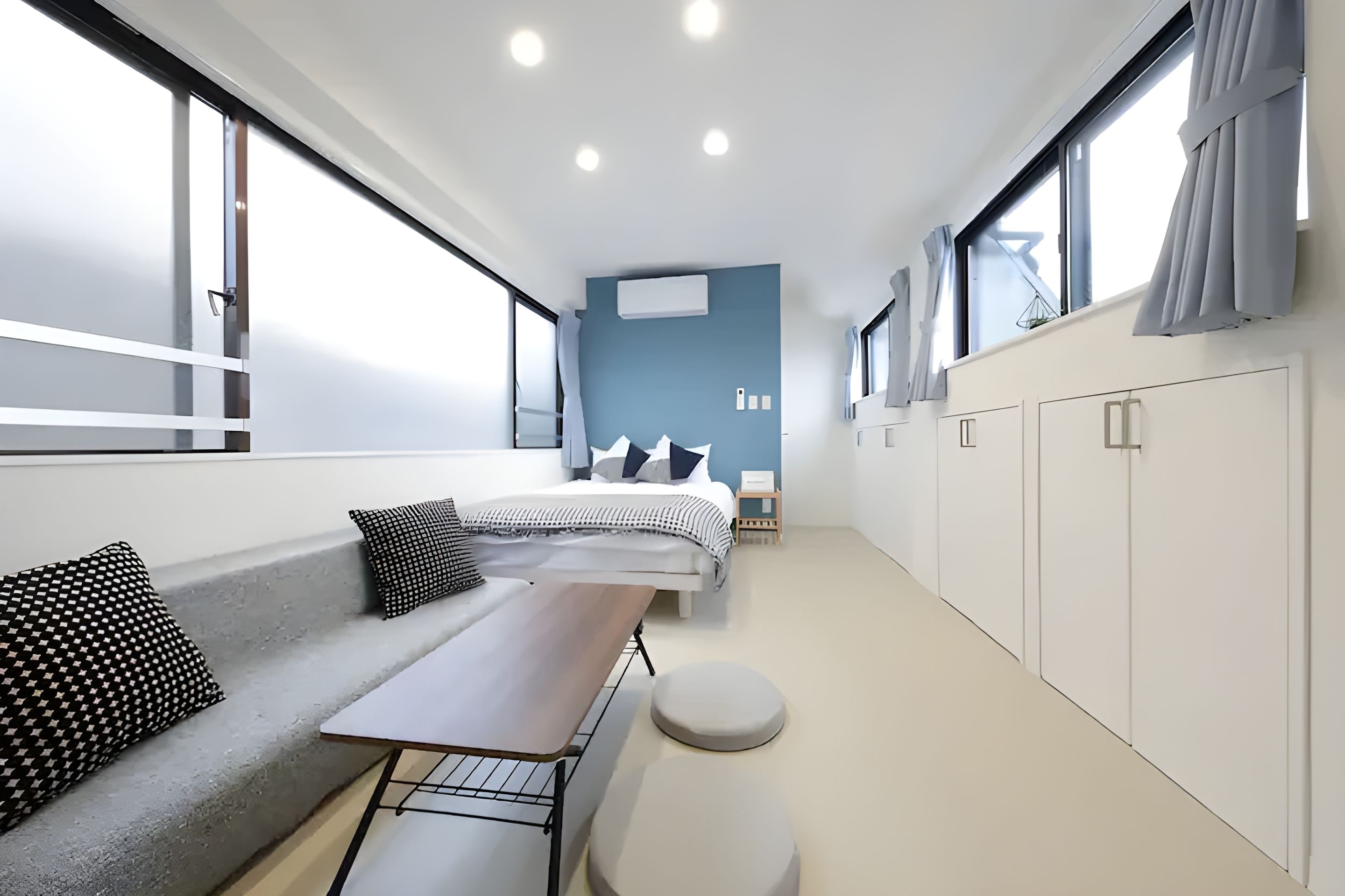 A modern, well-lit room with a large bed, a seating area with a table, and a wardrobe.