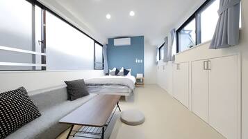 A modern, well-lit room with a large bed, a seating area with a table, and a wardrobe.