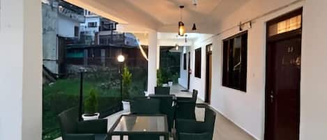 A corridor with a dining area featuring tables and chairs, a hanging light fixture, and a view of the outside.