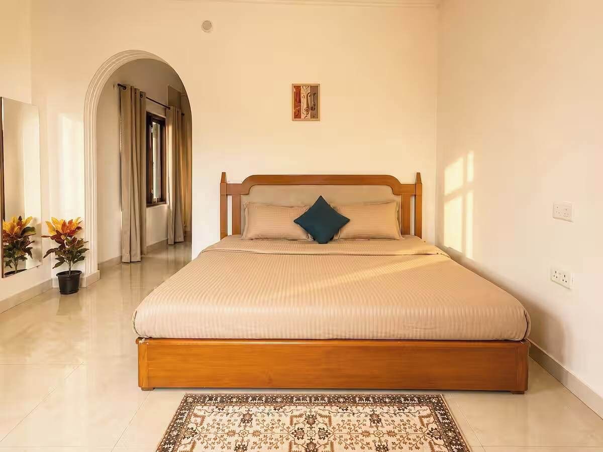 Ein Schlafzimmer mit einem großen Bett, einem Holz-Kopfteil, einem gemusterten Teppich und einem kleinen Wandbild.