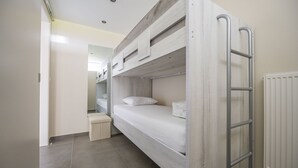 A bunk bed with a ladder, a small bedside table, and a radiator.