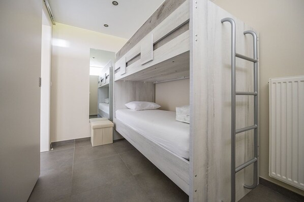A bunk bed with a ladder, a small bedside table, and a radiator.