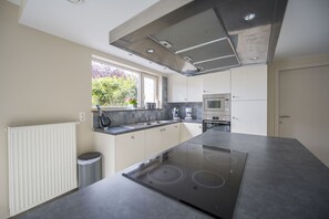 Una cocina moderna con una isla central, electrodomésticos integrados y un ventanal que proporciona luz natural.
