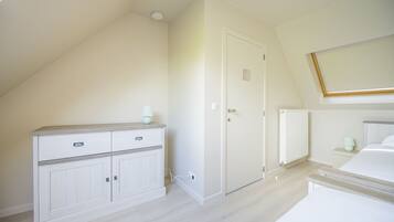A bedroom with a bed, a dresser, a door, and a radiator.