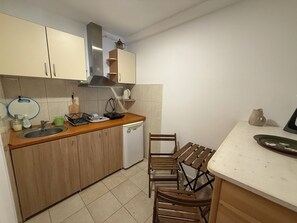 A compact kitchen with a dishwasher, wooden cabinets, a sink, and a dining area with a table and chairs. - Maslinada - Studio in peaceful fisherman village Bigova (Bigova)