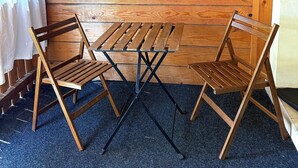 Interior de madera con una mesa y sillas, estantes con plantas y un techo con vigas a la vista.