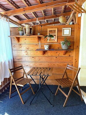 A wooden interior with a table and chairs, shelves with plants, and a ceiling with exposed beams. - Maslinada - Studio in peaceful fisherman village Bigova (Bigova)