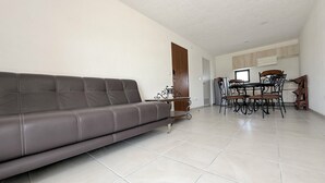 A living room with a sofa, a dining table with chairs, and a kitchen area in the background. - The perfect apartment for relaxing (El Marquez)
