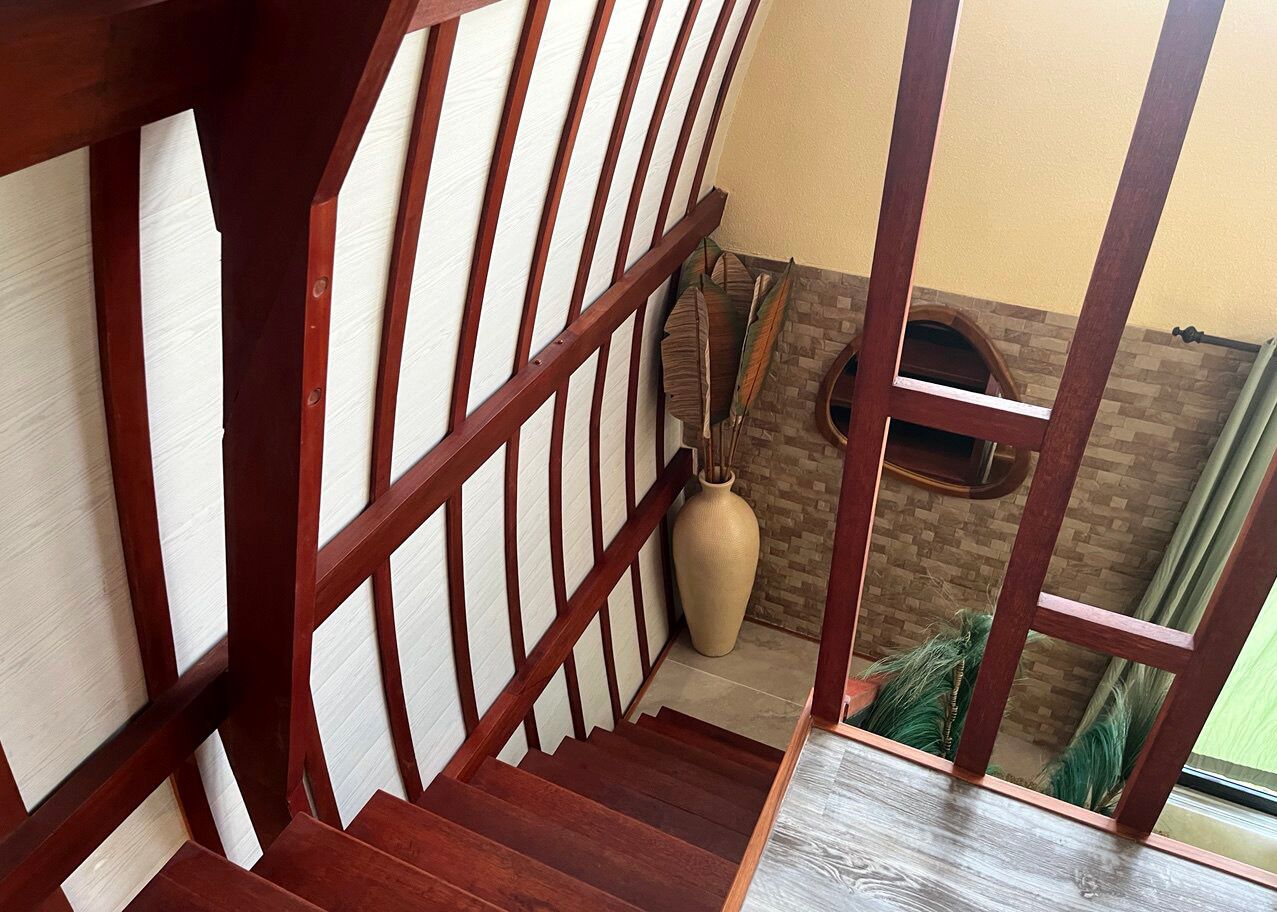 A wooden staircase with a view of a brick wall and a large vase.