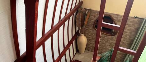 A wooden staircase with a view of a brick wall and a large vase.