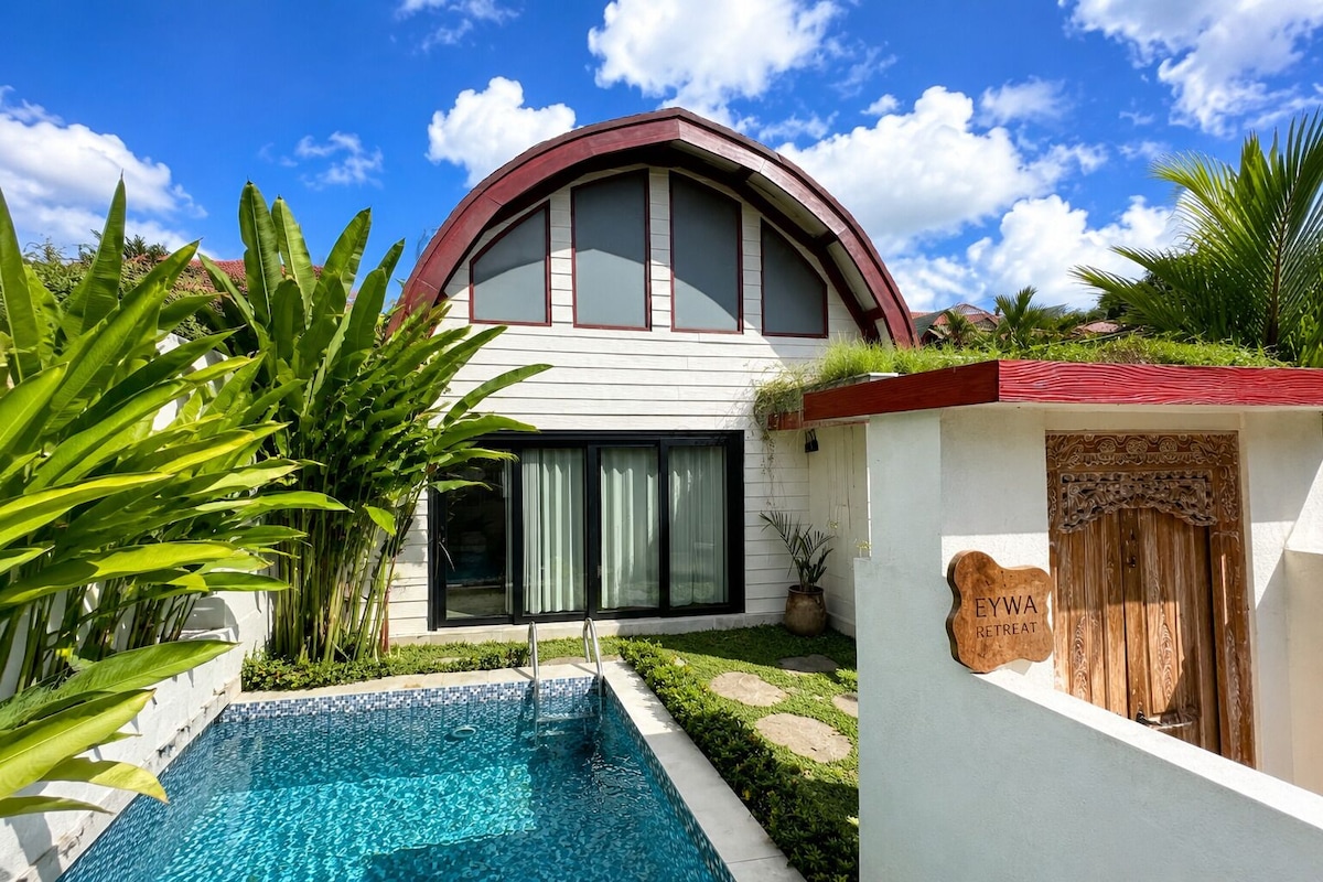 A modern house with a swimming pool, a curved roof, and a sign that reads 'EYWA RESTREAT'.