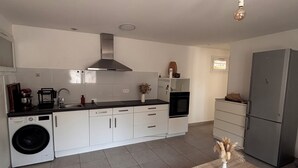 Eine moderne Küche mit weißen Schränken, einer eingebauten Waschmaschine und einem grauen Kühlschrank.