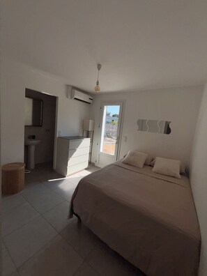 Un dormitorio con cama, mesita de noche, espejo y puerta que da a un balcón.