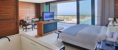 Habitación de hotel con una cama grande, televisión, escritorio y vista al océano.