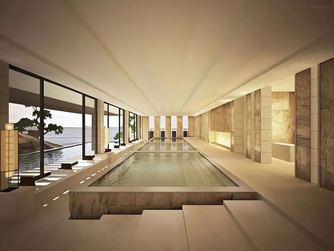 Un interior moderno con una larga piscina reflectante, ventanas amplias y vista al mar.