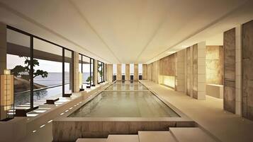 Un interior moderno con una larga piscina reflectante, ventanas amplias y vista al mar.