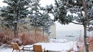 Ein mit Schnee bedeckter Sitzbereich im Freien mit Blick auf das Meer.
