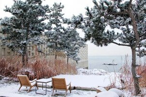 A snow-covered outdoor seating area with a view of the sea.