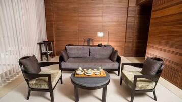A modern living room with a sofa, two armchairs, a coffee table, and a side table with a lamp.