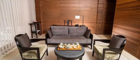 Una sala de estar moderna con un sofá, dos sillones, una mesa de centro y una mesita de noche con una lámpara.