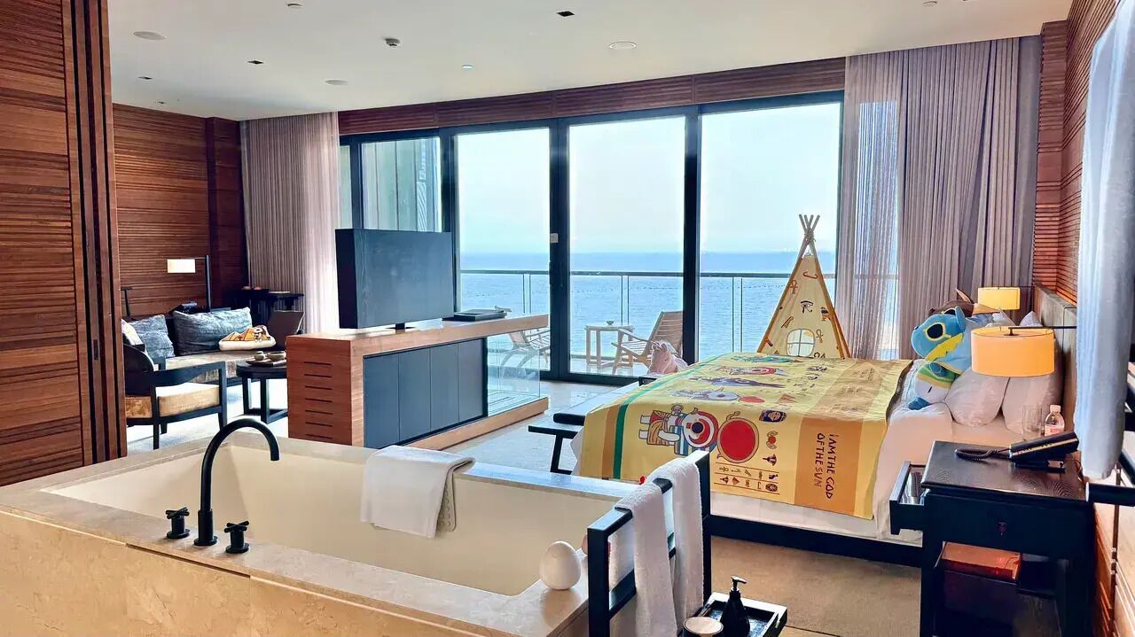 Une chambre d’hôtel avec une grande fenêtre, un lit, un bureau et une salle de bain.