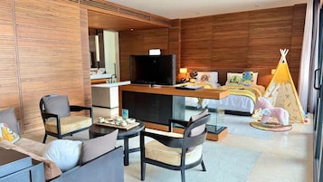 Una habitación de hotel moderna con televisor, sofá, sillas, escritorio y cama decorada con un dosel.