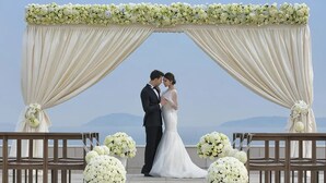 A couple standing under a floral arch with a view of the sea. - The Lalu Qingdao (Qingdao)