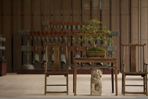 Una habitación tradicional con una mesa de madera, una planta en maceta y una estatua de león de piedra.