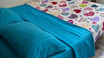 A bed with a blue blanket and a patterned bedspread.
