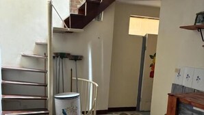 A staircase leading to an upper floor, a trash can, a wooden cabinet, and a patterned floor. - Casa Del Pueblo, Room Esplendor (Jardín)