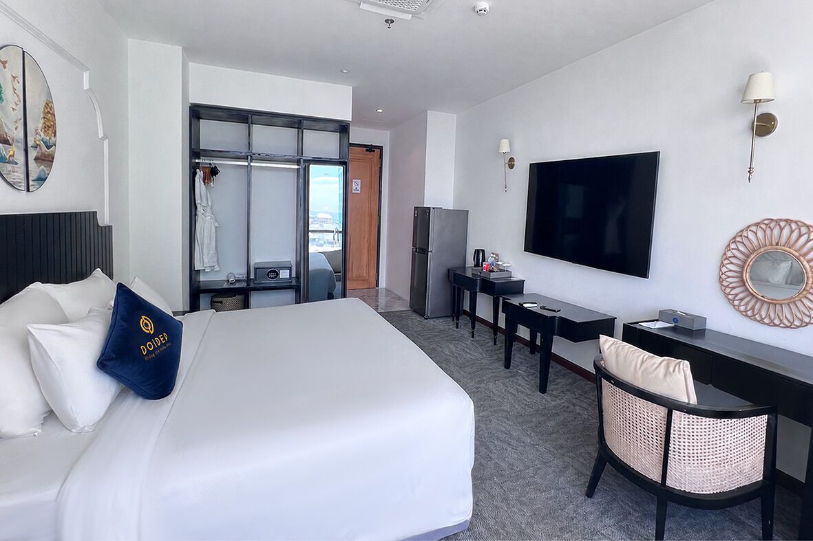 A hotel room with a bed, a desk, a television, and a wardrobe.