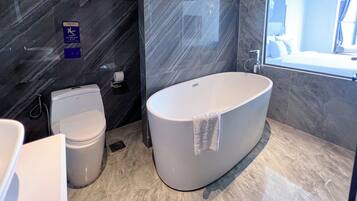 Une salle de bain moderne avec une baignoire sur pieds, des toilettes et un espace douche.