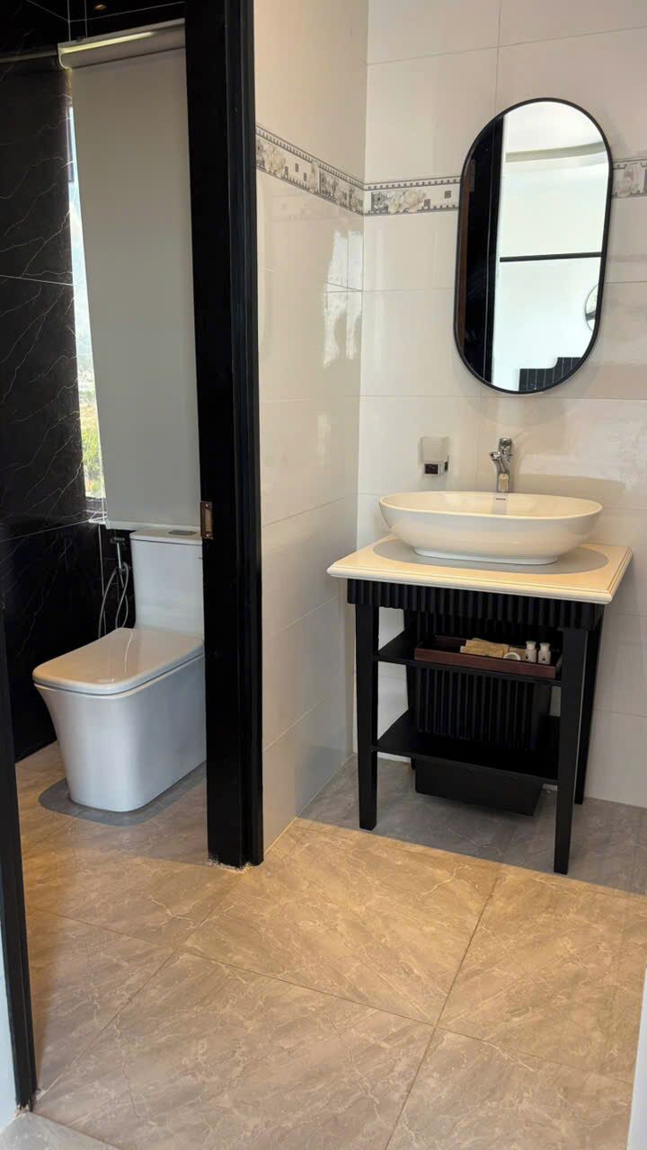 A bathroom with a white sink, a round mirror, and a toilet.