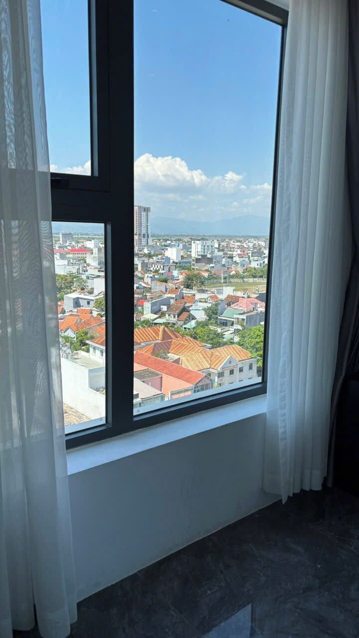 A room with a large window offering a view of a cityscape.