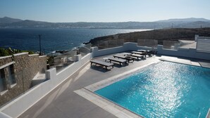 Zona de piscina con sillones de descanso y vista al mar.