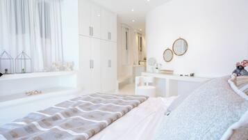 Un dormitorio moderno con una cama grande, un tocador con espejos y un vestidor.